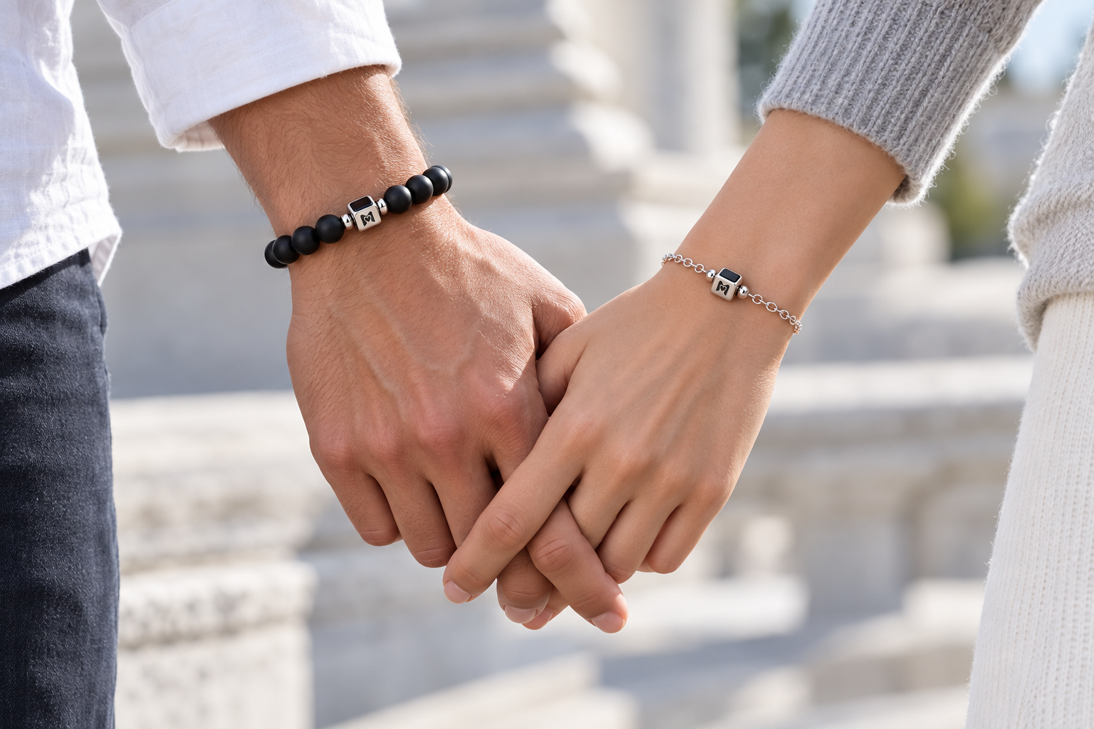 Zwei Menschen halten Händchen und tragen Moments Armbänder mit kleinem silbernem Mittelstück